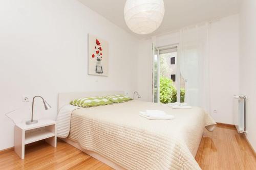 a white bedroom with a bed and a sink at Kuvi Apartments in Rovinj