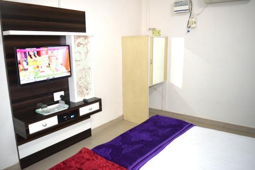 a living room with a tv and a purple rug at Hotel Gokul in Kota
