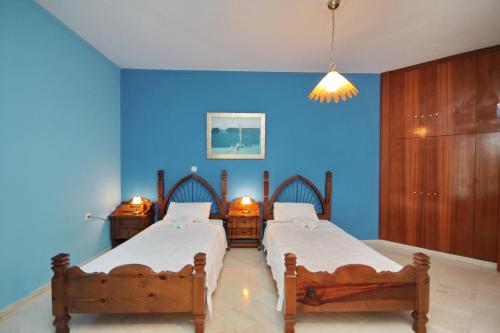 two beds in a room with a blue wall at Hotel Marialena in Ancient Epidauros