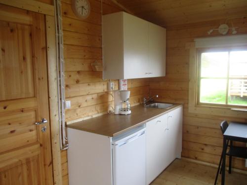eine Küche mit weißen Schränken, einem Waschbecken und einem Fenster in der Unterkunft Fálki cottages in Þórshöfn