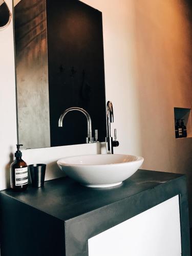 a white sink on a black counter with a mirror at AVLiving City LOFT Basel in Basel
