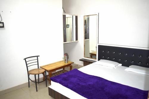 a bedroom with a bed and a table and a chair at Hotel Gokul in Kota