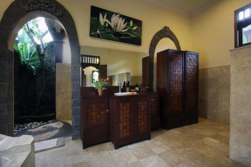 een badkamer met twee houten deuren en een wastafel bij Nara Ubud Cottage by Mahaputra in Ubud