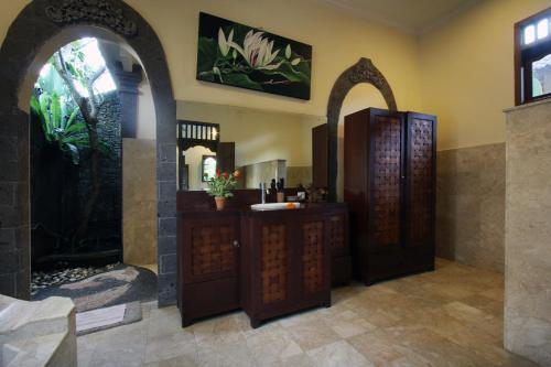 a bathroom with two wooden doors and a sink at Nara Ubud Cottage by Mahaputra in Ubud