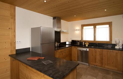 una cocina con nevera de acero inoxidable y armarios de madera en Odalys Chalet Levanna Orientale, en Les Deux Alpes