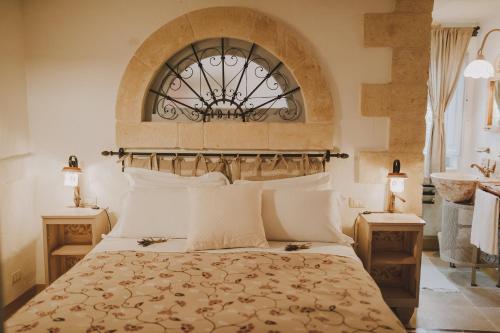 a large white bed sitting in a bedroom next to a window at Masseria Montenapoleone in Pezze di Greco