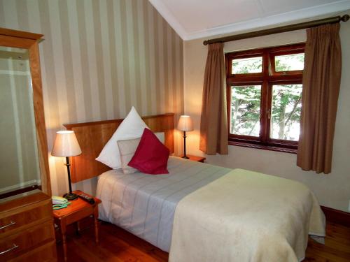 a bedroom with a bed with two lamps and two windows at Clarence House in Cape Town