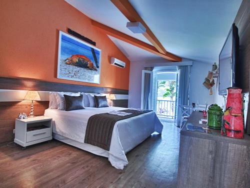 a bedroom with a bed with an orange wall at Costa Verde Tabatinga Hotel in Caraguatatuba