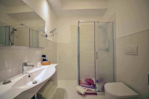 een badkamer met een douche, een wastafel en een toilet bij Hotel Corona Beach Peschici in Peschici
