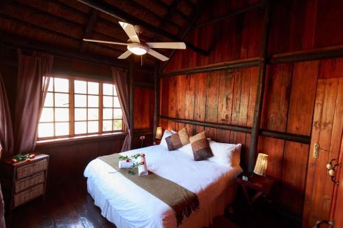 a bedroom with a bed with a ceiling fan at Rain Farm Game Lodge in uMhlali