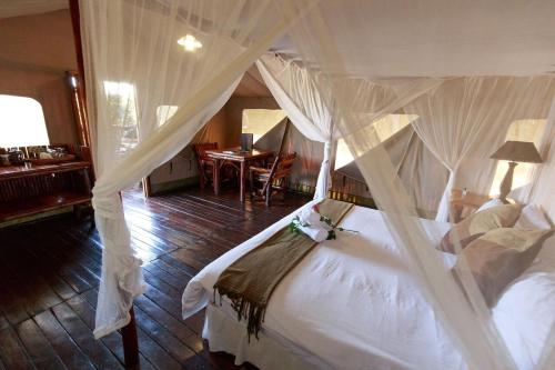 a bedroom with a white bed with a canopy at Rain Farm Game Lodge in uMhlali