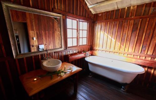 a wooden bathroom with a tub and a sink at Rain Farm Game Lodge in uMhlali