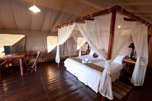 a bedroom with a canopy bed in a tent at Rain Farm Game Lodge in uMhlali