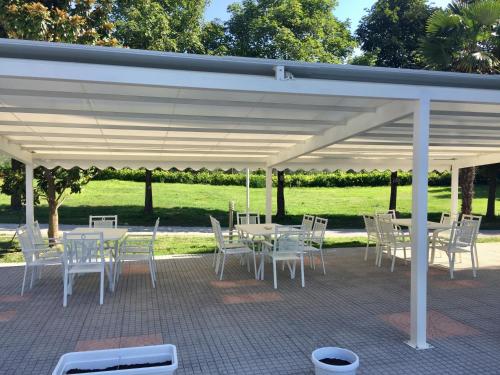 a patio with white tables and chairs under a pavilion at Aktiv Hotel Eden in Dro