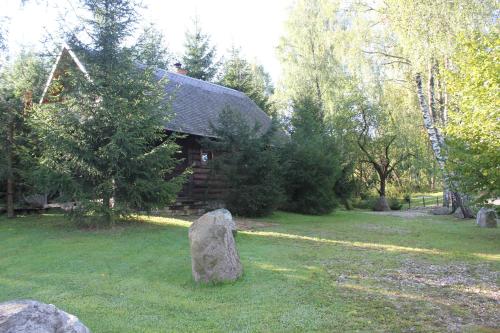 a stone in the grass in front of a cabin at Prie Klykio in Utena