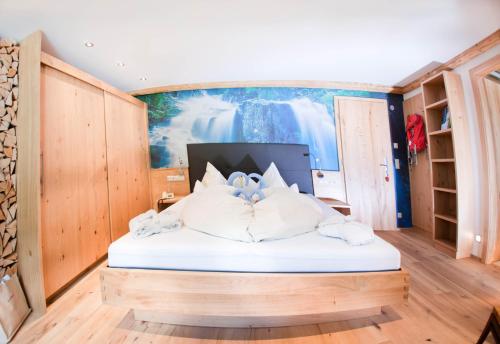 a bed in a room with a painting on the wall at Hotel Riederhof- Urlaub mit WAU! in Ried im Oberinntal