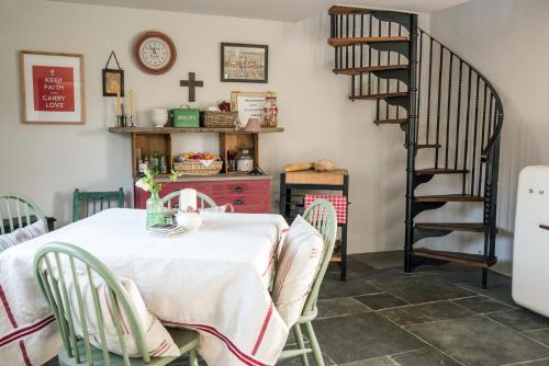 a dining room with a table and a spiral staircase at The Annexe in Chipping Campden