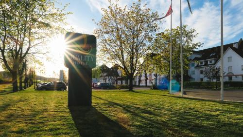 a sign in the grass with the sun in the background at Quality Hotel Olavsgaard in Skjetten