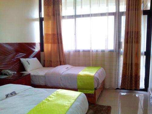 a hotel room with two beds and a window at Hotel OK Kampala in Kampala