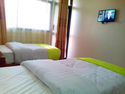 a hotel room with two beds and a flat screen tv at Hotel OK Kampala in Kampala