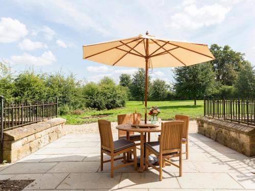 a table and chairs with an umbrella on a patio at Castle Gatehouse in Winchcombe