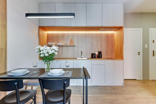a kitchen with a table and chairs and a kitchen with white cabinets at Blue Mandarin Riverside in Gdańsk