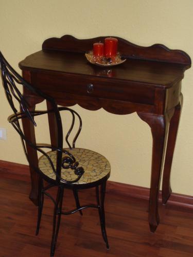 a wooden table with a chair and two red candles at Villa Gaia - Luxury Villa, pool & wellness rooms in Bordighera