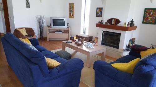 a living room with two blue chairs and a table at Villa da Praia Azul in Silveira