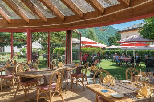 a patio with tables and chairs and people sitting at tables at Hotel La Romantica in Le Prese, Poschiavo
