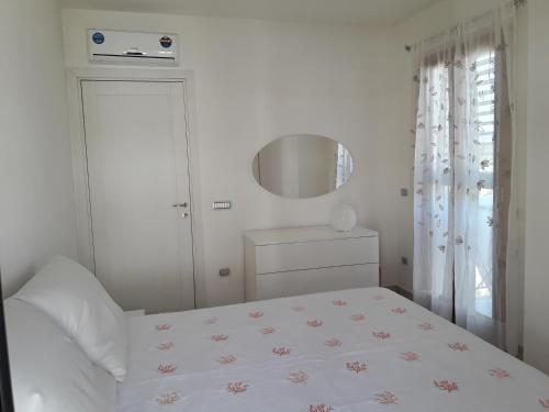 アルバタックスにあるCasa Lisa a Porto Frailisの白いベッドルーム(ベッド1台、鏡付)