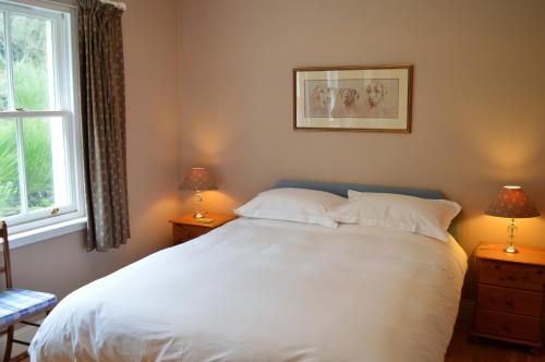 a bedroom with a large white bed with two lamps at Teal Cottage in Clachan of Glendaruel