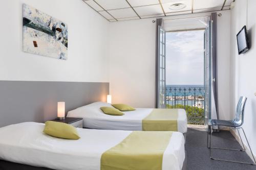 a hotel room with two beds and a balcony at Hotel El Paradiso in Menton