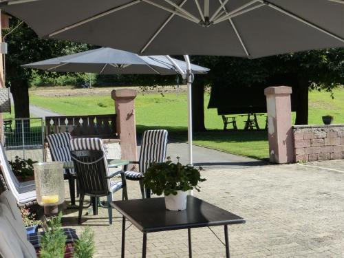 una mesa y sillas con una sombrilla en el patio en Ferienwohnungen Zur Mühle, en Mossautal