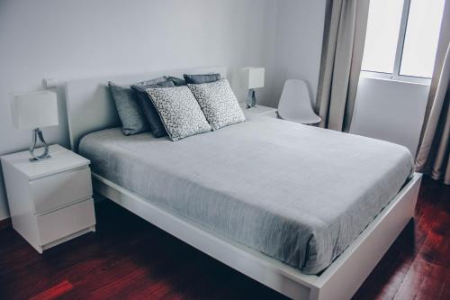 sypialnia z białym łóżkiem i białą szafką nocną w obiekcie Horizon View Madeira w Caniço