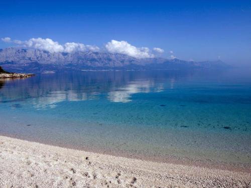 a beach with blue water and mountains in the background at Vila Vera Seafront Apartments in Sumartin