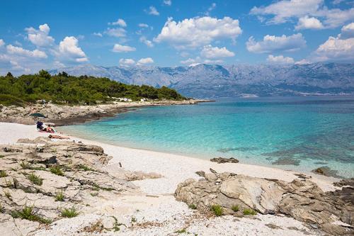 a beach with blue water and mountains in the background at Vila Vera Seafront Apartments in Sumartin