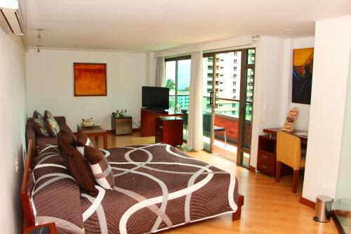 1 dormitorio con 1 cama y balcón con TV en Hotel Casa Victoria en Medellín