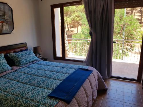 Schlafzimmer mit einem Bett mit blauer Bettwäsche und einem Fenster in der Unterkunft Chalet Asmoun in Imouzzer du Kandar