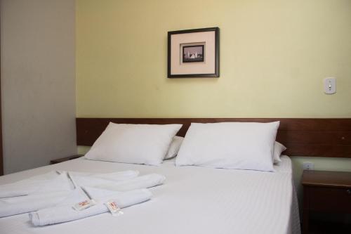 a bed with white pillows and two towels on it at Pousada da Mata in Iriri