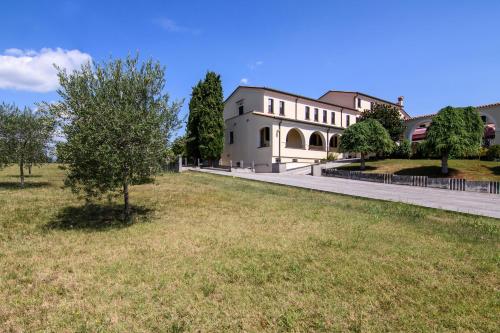 a large white house with a tree in a field at Hotel San Marco in Montebelluna