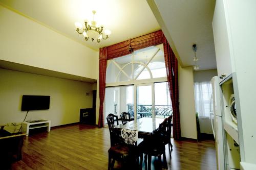 a dining room with a table and chairs and a television at Jennyville Pension in Seogwipo