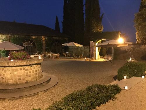 a patio with a stone wall and tables and umbrellas at night at Agriturismo Antica Dimora Del Turco in Sona