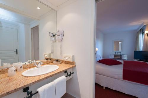 a bathroom with a sink and a bedroom with a bed at Avignon Grand Hotel in Avignon