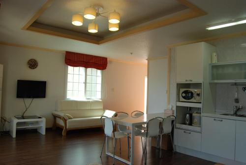 a kitchen and living room with a table and chairs at Jennyville Pension in Seogwipo