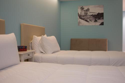 a bedroom with two beds and a table with a picture on the wall at Feira Hostel & Suites in Santa Maria da Feira