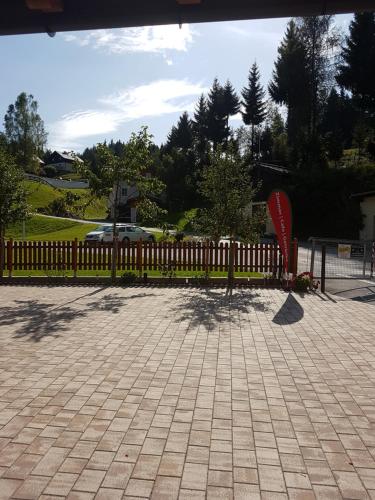 a fence with a red object next to a sidewalk at Pension Haus Rohrmoser in Annaberg im Lammertal