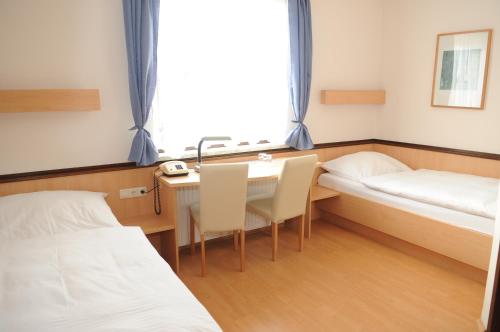 a room with two beds and a desk and a table at Innviertlerhof in Linz