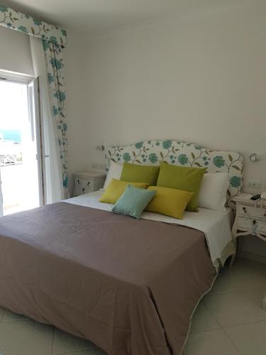 a bedroom with a large bed with yellow and green pillows at Casa Gaia in Capri