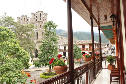 a balcony with potted plants and a church at Hotel Valdivia Plaza in Jardin