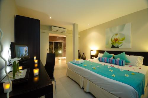 Schlafzimmer mit einem Bett, einem Schreibtisch und einem TV in der Unterkunft Ocean Villas Hotel in Grand Baie